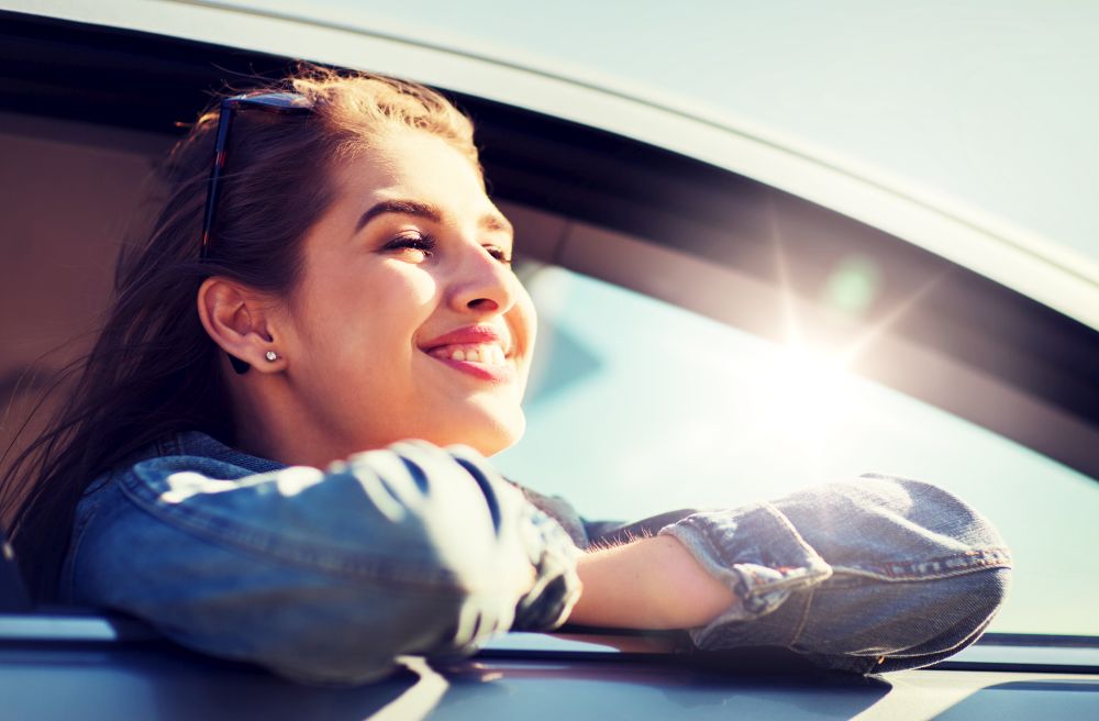 summer vacation, holidays, travel, road trip and people concept - happy smiling teenage girl or young woman in car. happy teenage girl or young woman in car