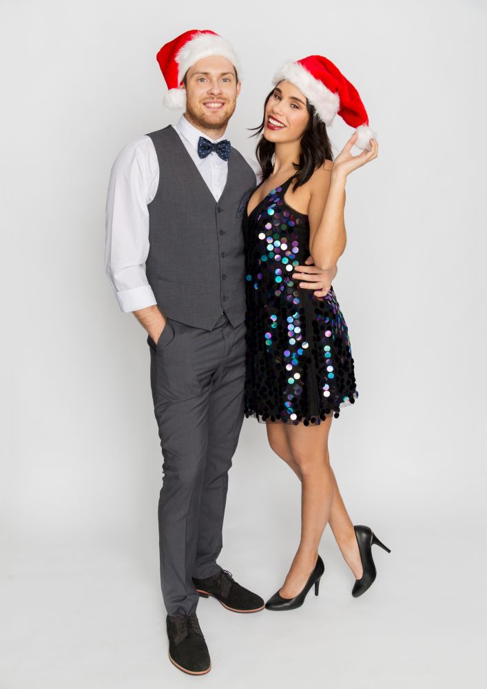 celebration, people and holidays concept - happy couple in santa hats at christmas or new year party. happy couple in santa hats at christmas party