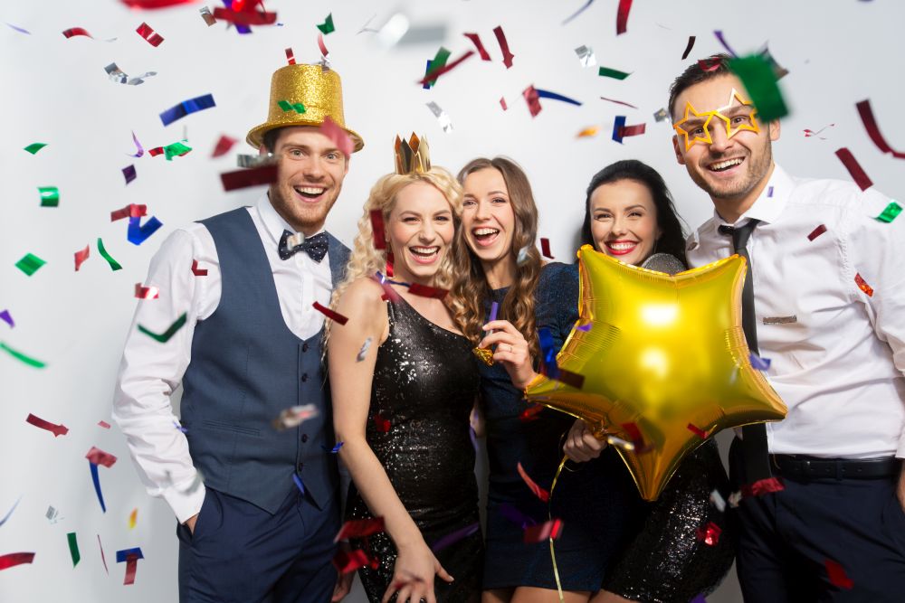 celebration, fun and holidays concept - happy friends with golden party props and confetti laughing. friends with party props and confetti laughing