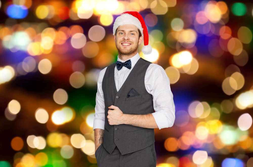 christmas, people and holidays concept - happy man in santa hat and vintage suit over festive lights background. happy man in santa hat and suit on christmas