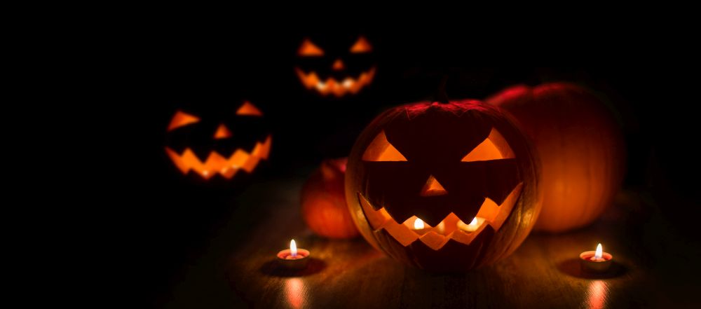 halloween and holidays concept - many spooky carved pumpkin jack-o-lanterns with candles in darkness. halloween jack-o-lanterns burning in darkness