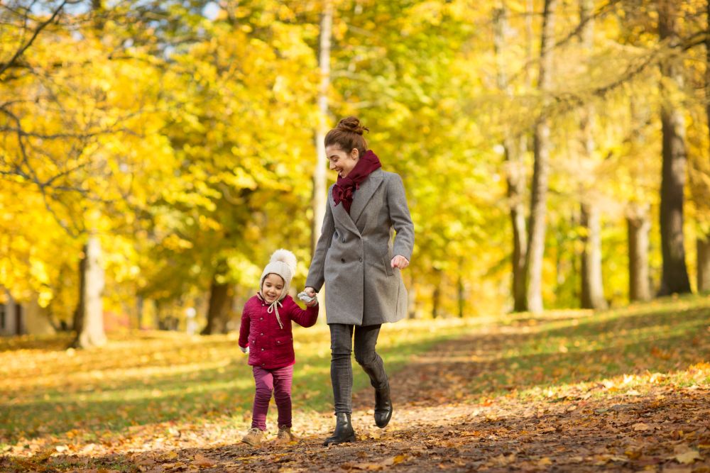 family, season and people concept - happy mother and little daughter walking along autumn park. happy mother and little daughter at autumn park
