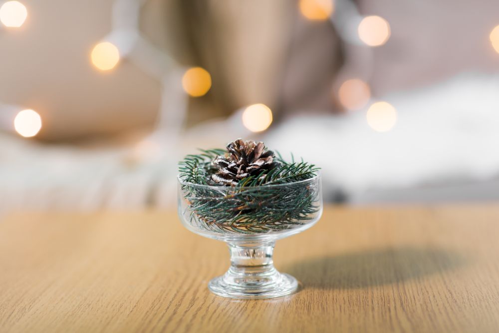 christmas concept - decoration of fir twig with pinecone in ice cream glass or dessert bowl. christmas fir decoration with cone in dessert bowl