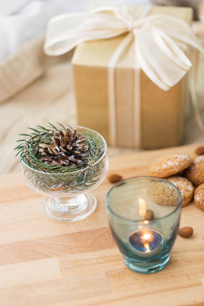 christmas concept - decoration of fir twig with pinecone in ice cream glass or dessert bowl, candle, oatmeal cookies and gift. christmas fir decoration, candle, cookies and gift