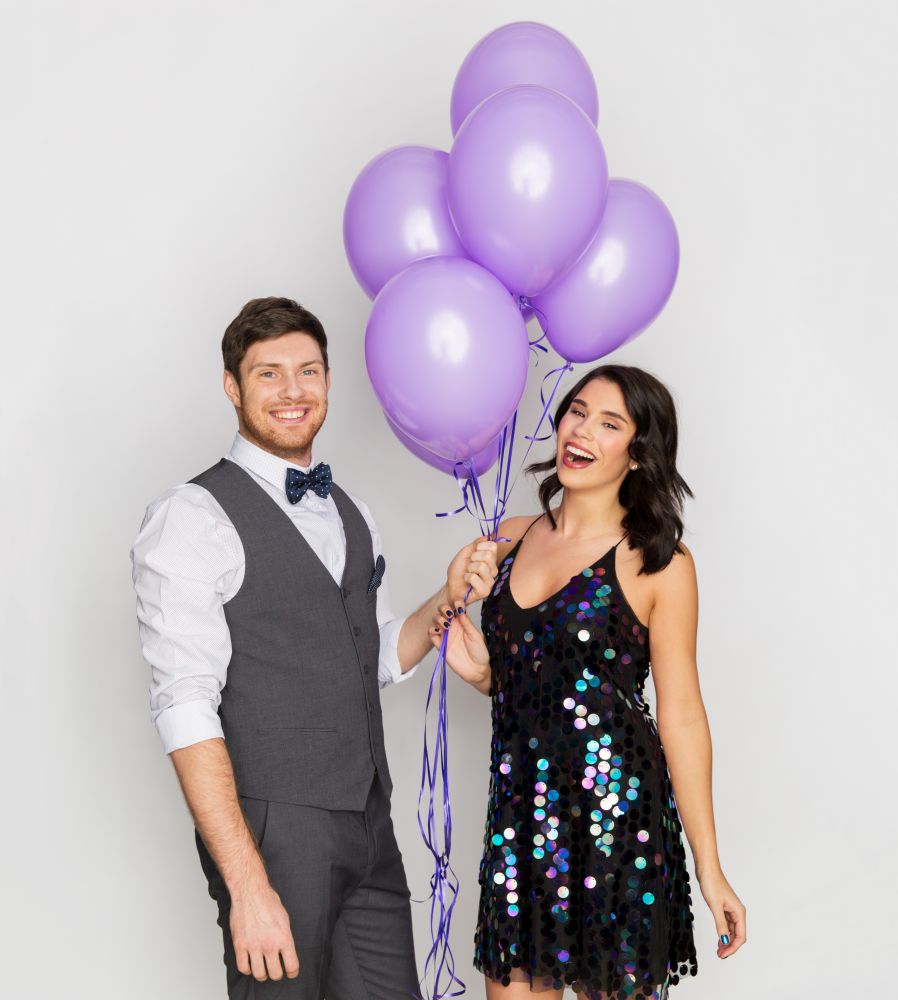 celebration, valentines day and holidays concept - happy couple with ultra violet balloons at birthday party. happy couple with ultra violet balloons at party