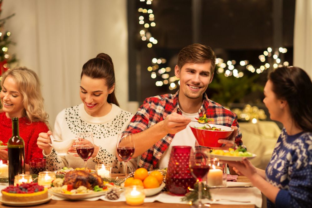 holidays and celebration concept - happy friends having christmas dinner at home and eating. happy friends having christmas dinner at home