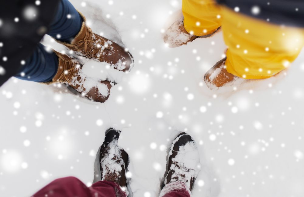season, friendship and people concept - feet on snow. group of people feet on snow