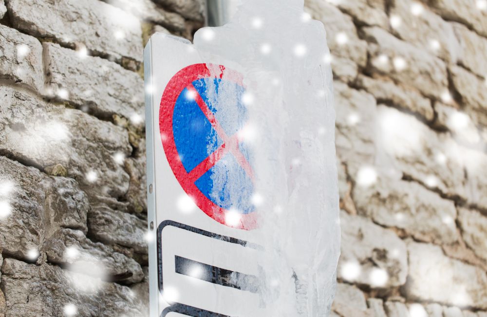 season, traffic and winter concept - iced no stopping road sign over wall. ice-covered no stopping road sign over wall