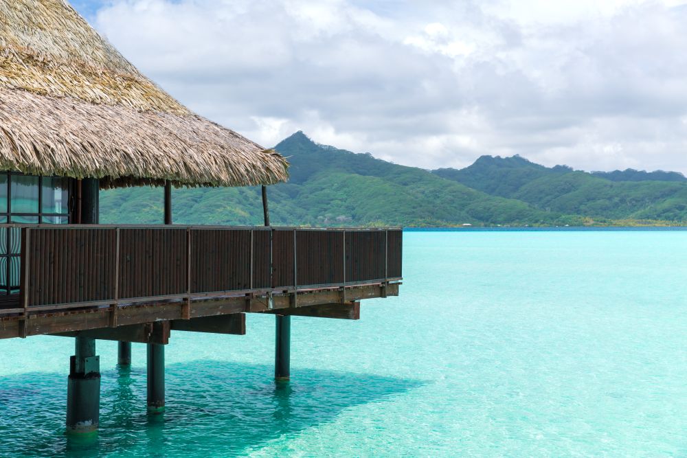 travel, tourism, vacation and summer holidays concept - bungalow huts in sea on tropical resort of french polynesia. bungalow huts of resort in french polynesia