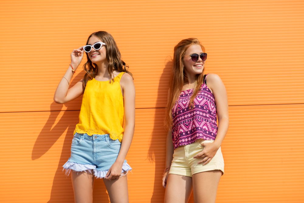 fashion, leisure and people concept - smiling teenage girls in summer clothes outdoors. smiling teenage girls in summer clothes outdoors