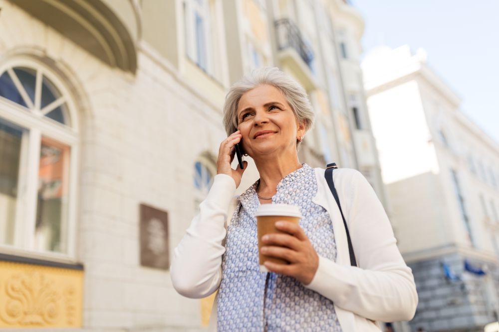 retirement, communication and old people concept - happy senior woman drinking coffee and calling on smartphone in summer city. senior woman calling on smartphone in city