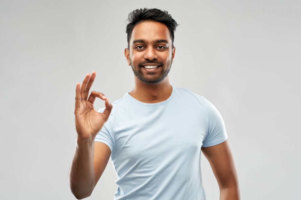 gesture and people concept - happy indian man in t-shirt showing ok hand sign over grey background. happy indian man in t-shirt showing ok hand sign