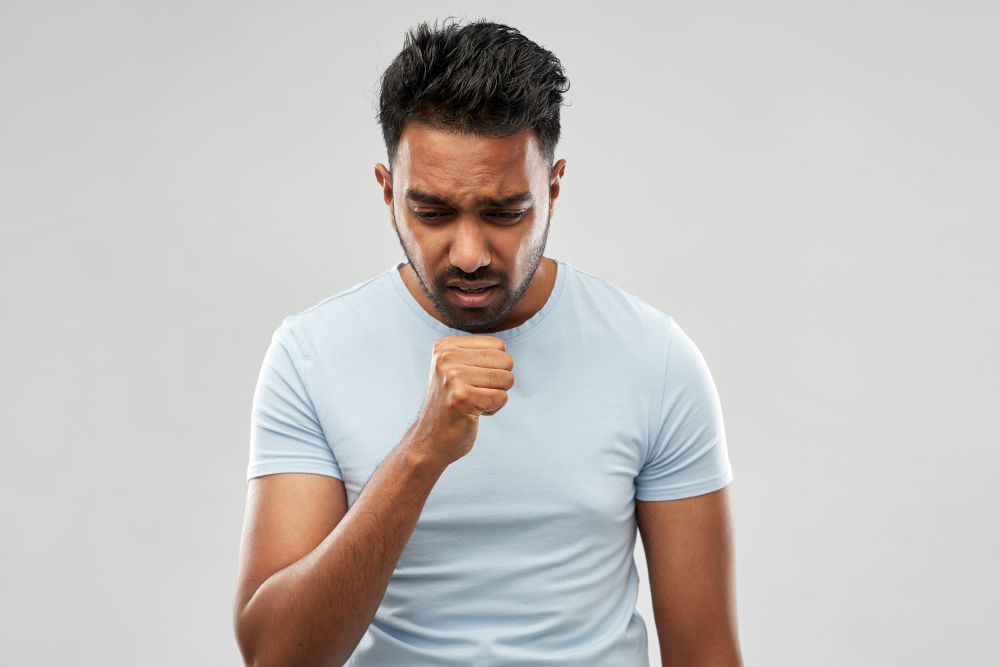 health problem and people concept - unhealthy indian man coughing over grey background. unhealthy indian man coughing