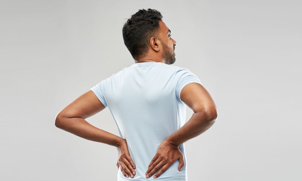 health problem and people concept - unhappy indian man suffering from pain in back or reins over grey background. indian man suffering from backache