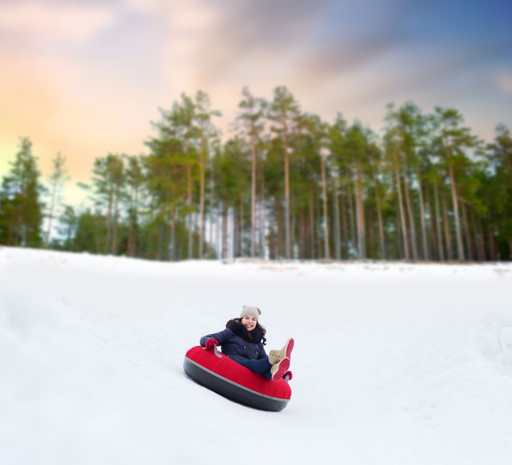winter, leisure and entertainment concept - happy teenage girl sliding down hill on snow tube. happy teenage girl sliding down hill on snow tube
