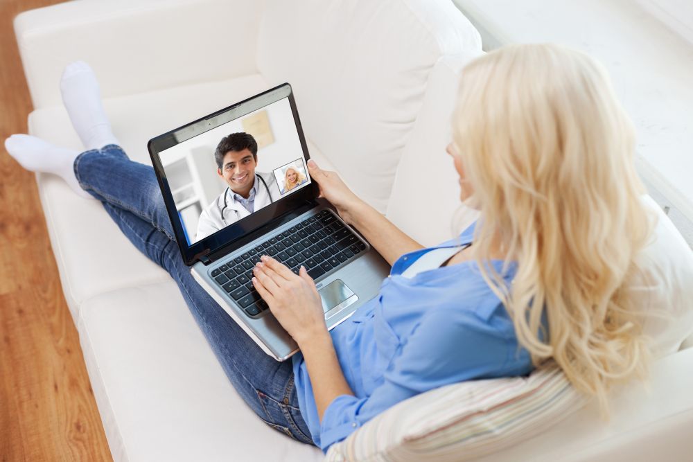 medicine, technology and healthcare concept - woman or patient having video call with male doctor on laptop computer at home. patient having video call with doctor on laptop