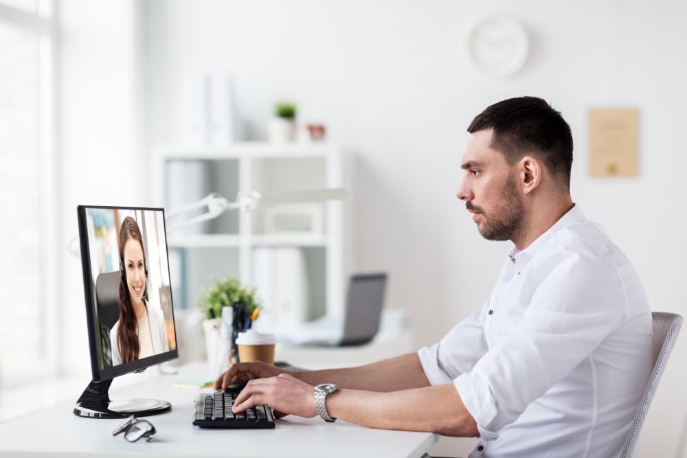 business, communication and technology concept - businessman having video call with customer service operator or partner on pc computer at office. businessman having video call on pc at office