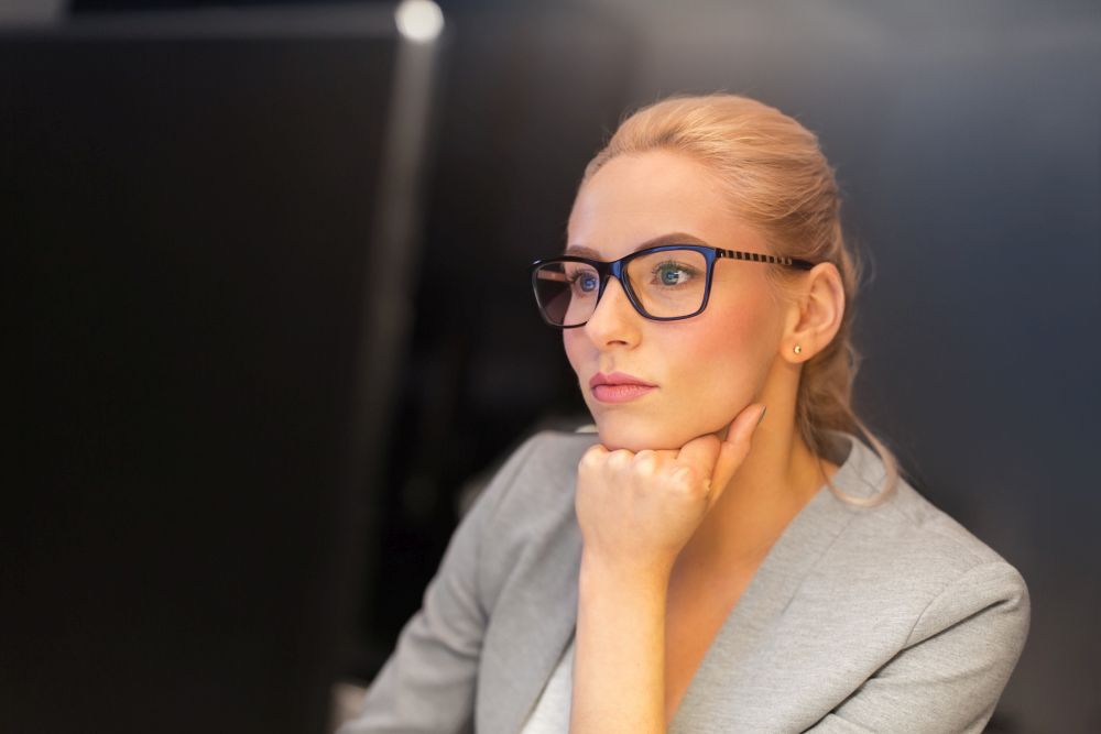 business, overwork, deadline and people concept - businesswoman in glasses working at computer in night office. businesswoman working at computer in night office