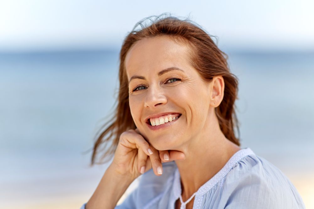 people and leisure concept - portrait of happy smiling woman on summer beach. portrait of happy smiling woman on summer beach