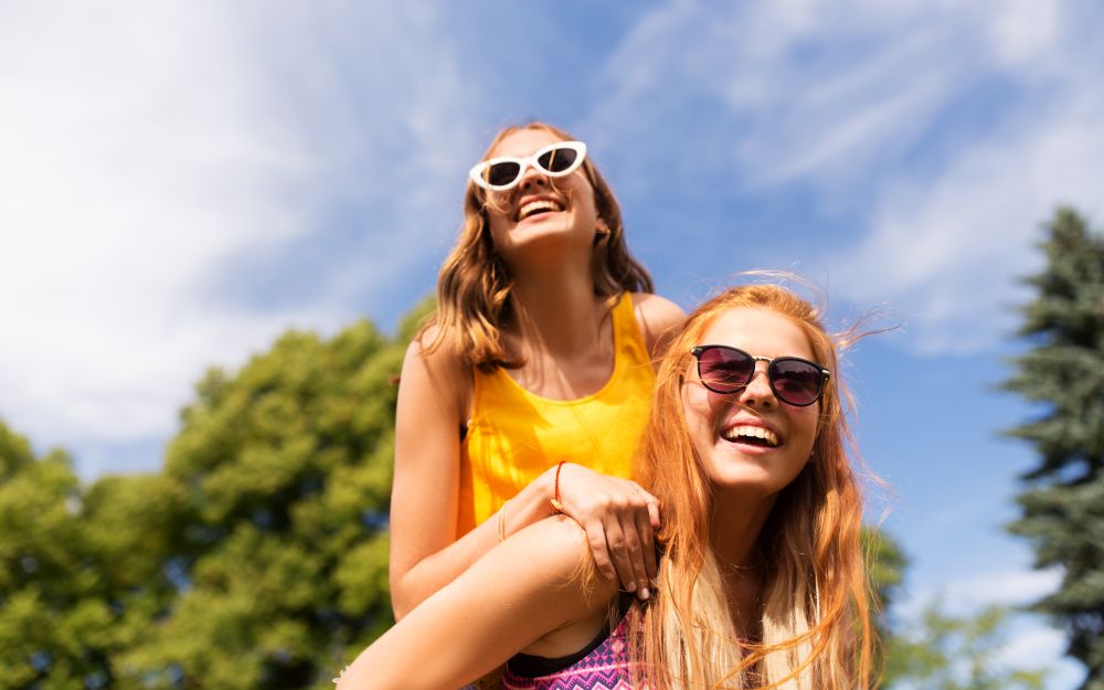 leisure, people and friendship concept - happy teenage girls or friends having fun at summer park. happy teenage girls having fun at summer park