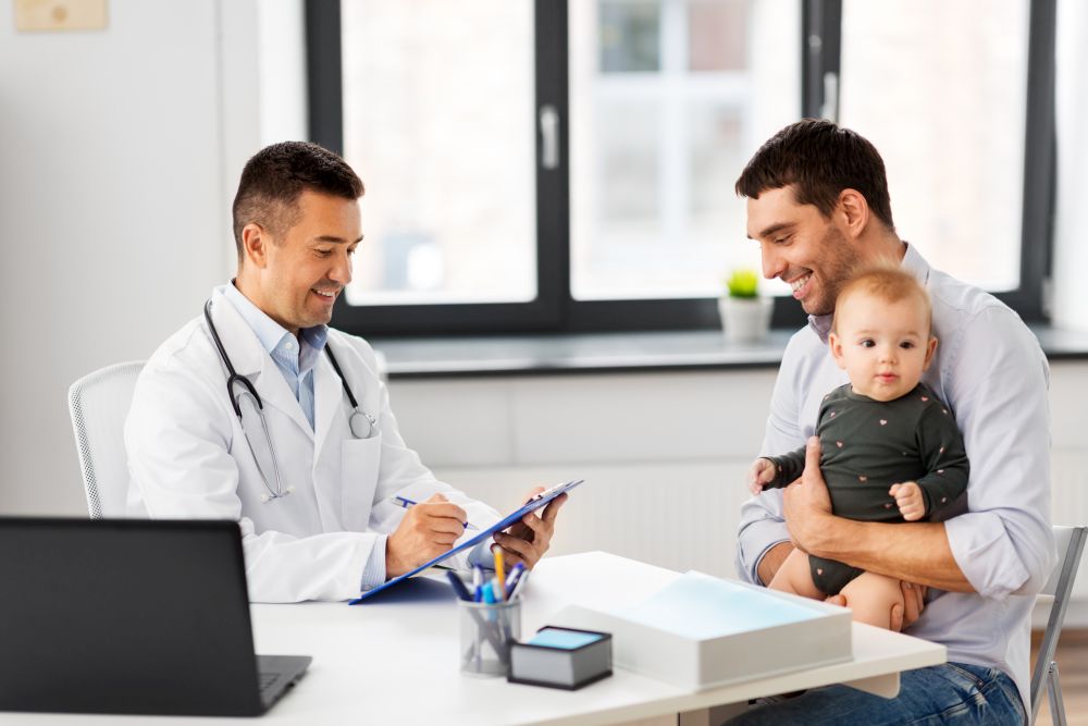 medicine, healthcare, pediatry and people concept - happy father with baby daughter and doctor with clipboard at medical office in hospital. father with baby and doctor at clinic