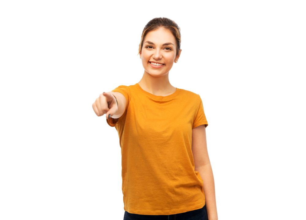 gesture and people concept - smiling young woman in blank orange t-shirt pointing finger at you over white background. young woman or teenage girl pointing finger at you