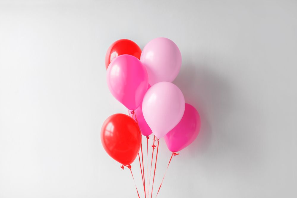 valentines day and birthday party decoration concept - bunch of pink and red air balloons over white wall. pink and red air balloons for birthday party