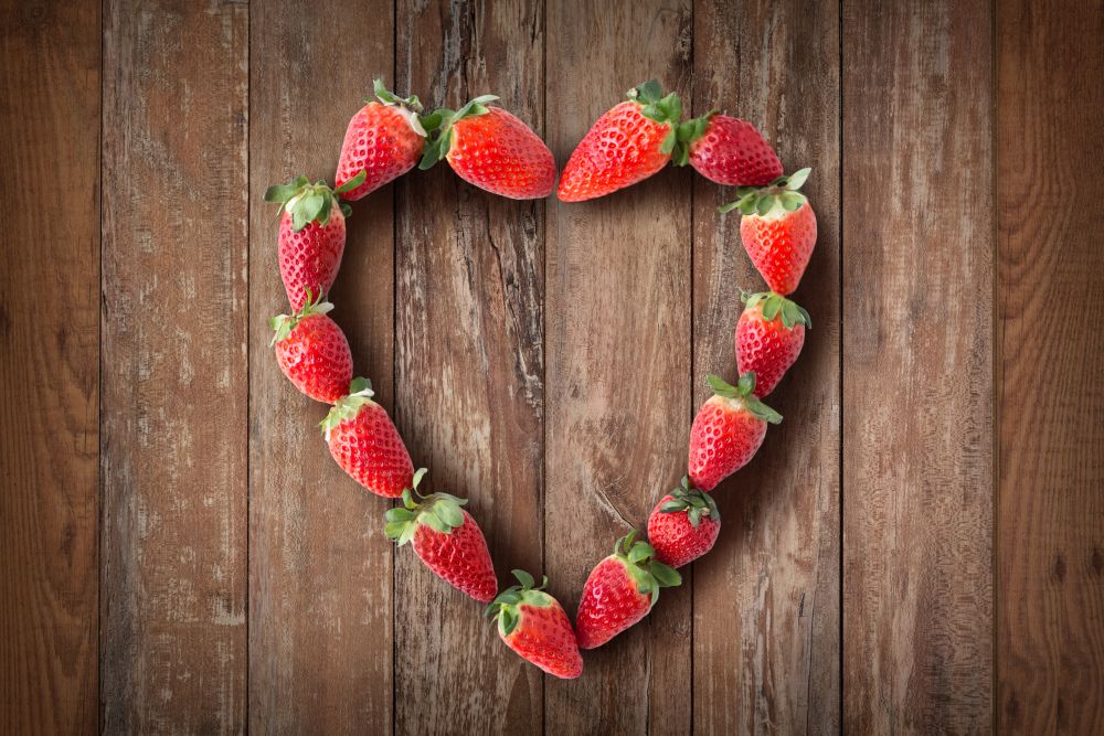 valentines day and romantic concept - heart shaped frame made of fresh strawberries. heart shaped frame made of fresh strawberries