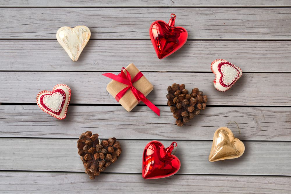 holidays and festive concept - christmas gift and heart shaped decorations over grey wooden boards background. christmas gift and heart shaped decorations