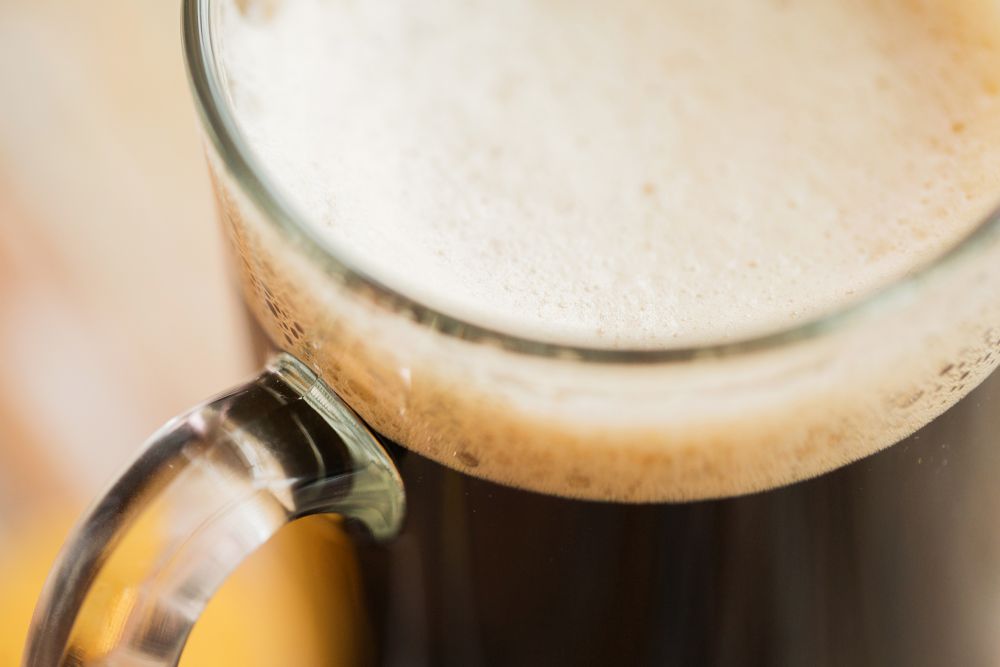 alcohol and drinks concept - close up of dark draft beer glass mug. close up of dark draft beer glass mug