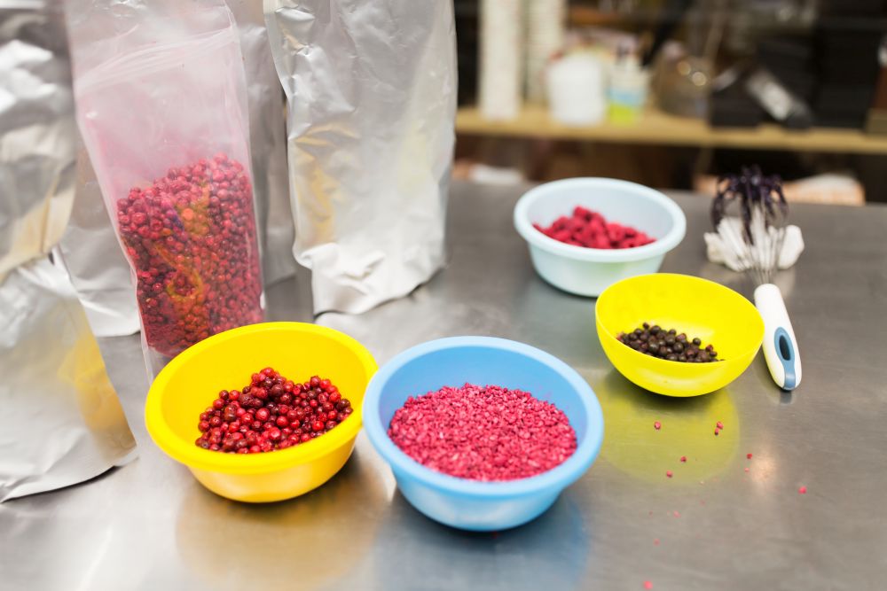 production, cooking and people concept - berries in bowls and whisk at confectionery shop kitchen. berries in bowls at confectionery shop kitchen