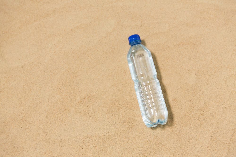 hydration and summer concept - bottle of water on beach sand. bottle of water on beach sand