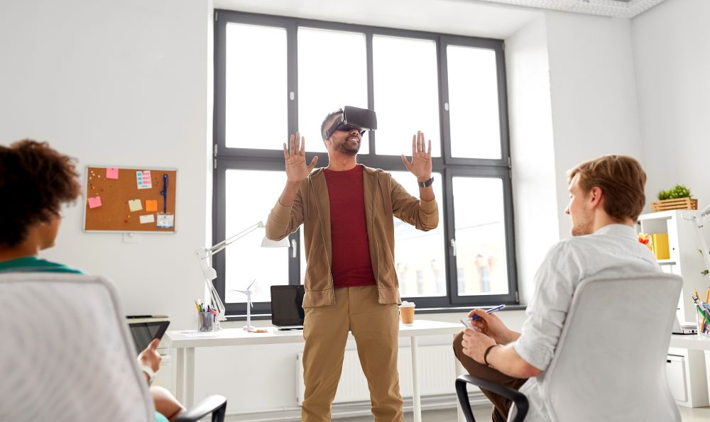 business, augmented reality and technology concept - creative team with tablet pc computer testing virtual headset or 3d glasses at office. developers with virtual reality headset at office