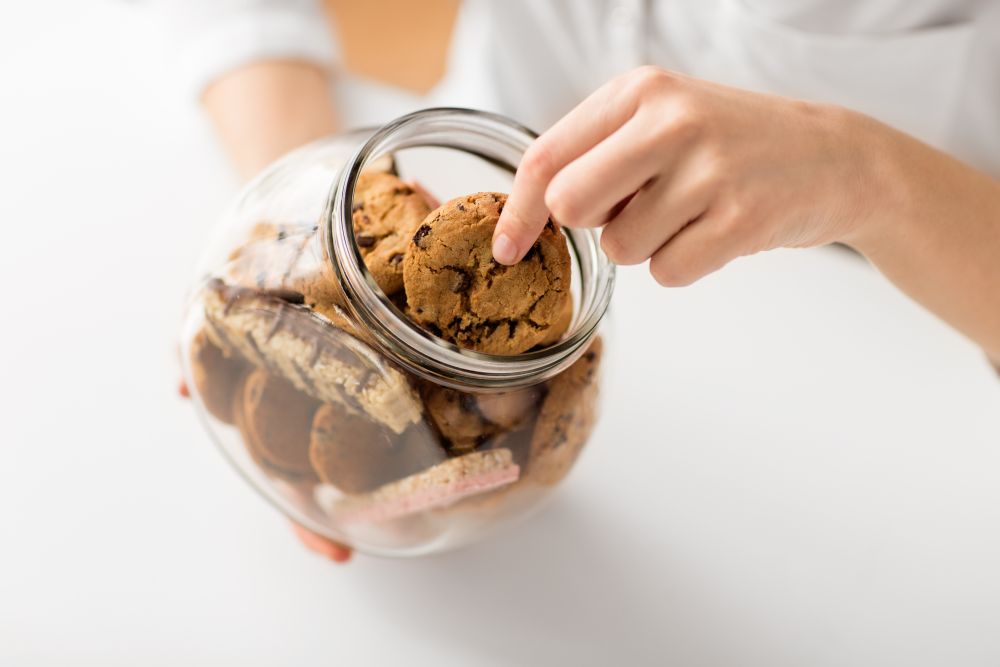 food, pastry and eating concept - close up of woman taking oatmeal cookies from glass jar. close up of woman taking oatmeal cookies from jar