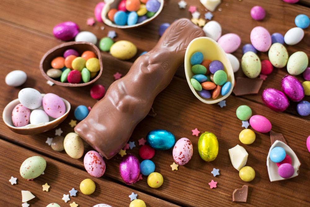 easter, sweets and confectionery concept - chocolate eggs, bunny and candy drops on wooden background. chocolate eggs, easter bunny and candies on wood
