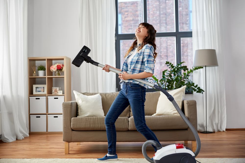 household, housework and cleaning concept - asian woman or housewife with vacuum cleaner having fun at home. asian woman with vacuum cleaner having fun at home