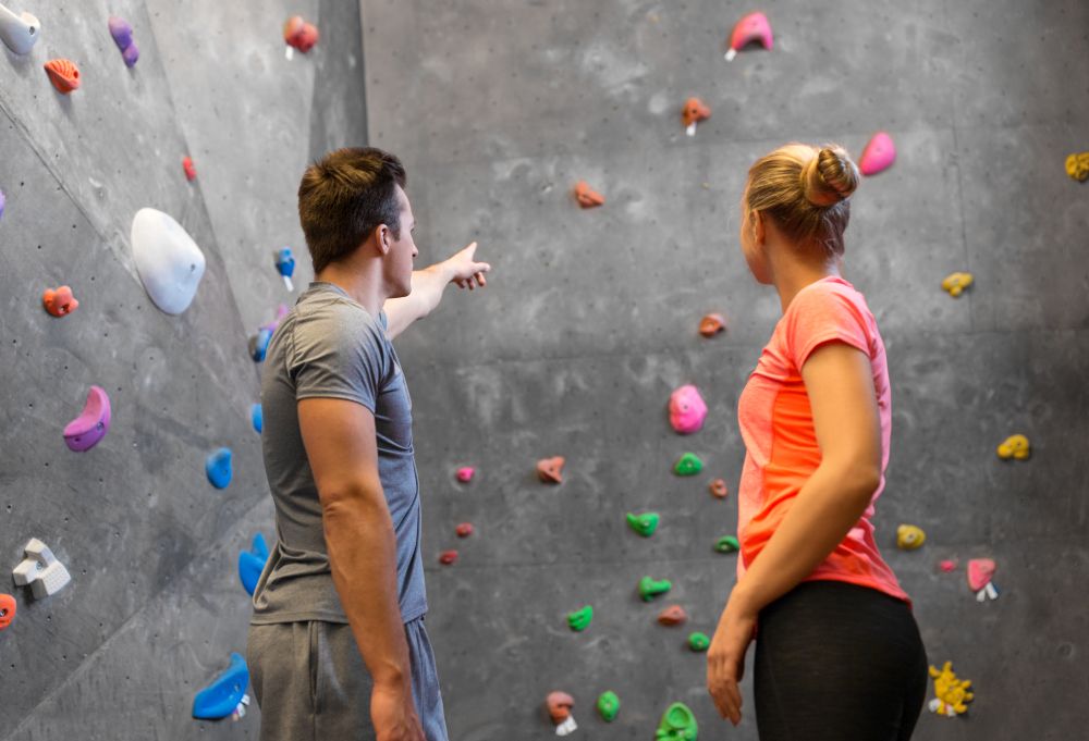 fitness, extreme sport and bouldering concept - man and woman exercising at indoor climbing gym. man and woman exercising at indoor climbing gym