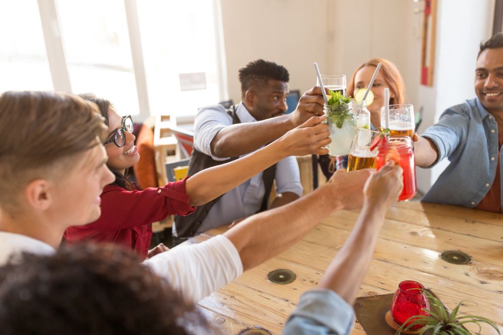 leisure, food and people concept - group of happy international friends clinking glasses at bar or restaurant. friends clinking glasses at bar or restaurant