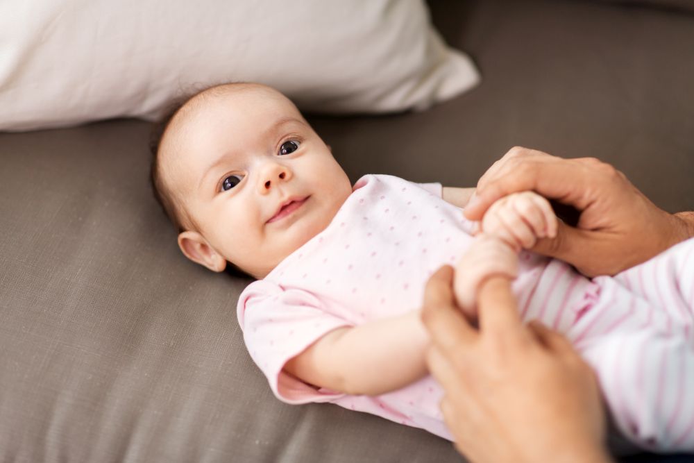 family, parenthood and fatherhood concept - close up of middle aged father playing with little baby daughter lying on sofa at home. middle aged father playing with baby at home