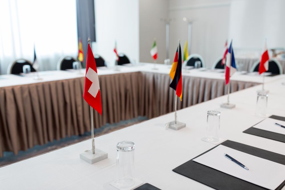business, corporate and interior concept - table with flags and paper in boardroom at international conference. table in boardroom at international conference
