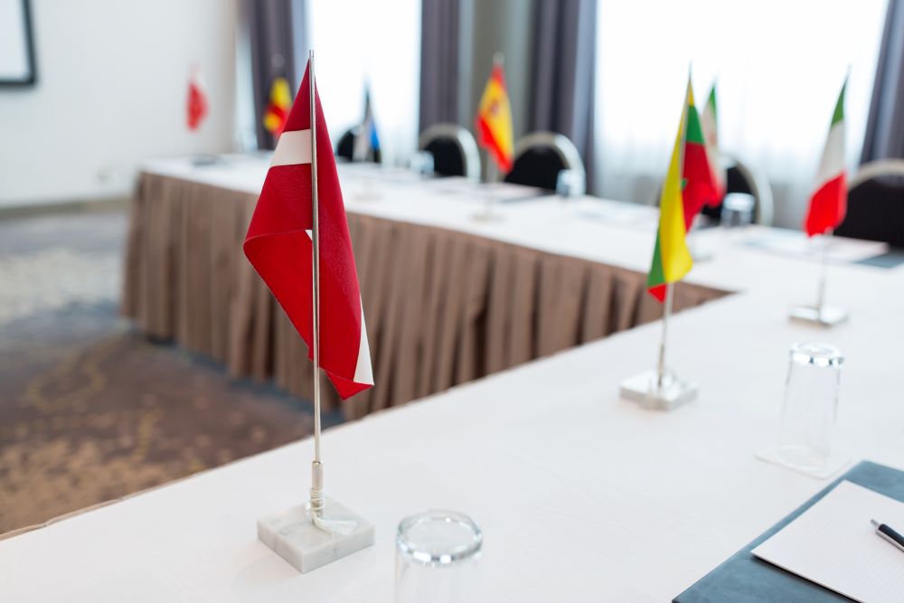 business, corporate and interior concept - flags on table in boardroom at international conference. flags at international conference boardroom