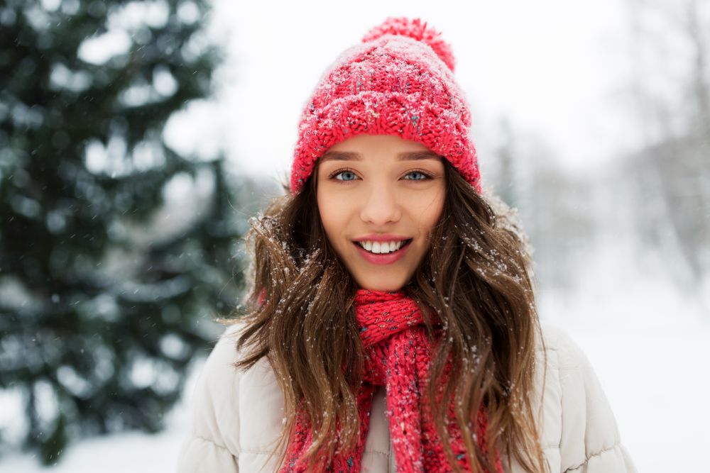people, season and christmas concept - portrait of happy smiling teenage girl or young woman outdoors in winter park. smiling teenage girl outdoors in winter