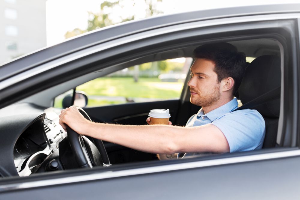 transport, vehicle and driving concept - tired sleepy man or car driver with takeaway coffee cup. tired man driving car with takeaway coffee
