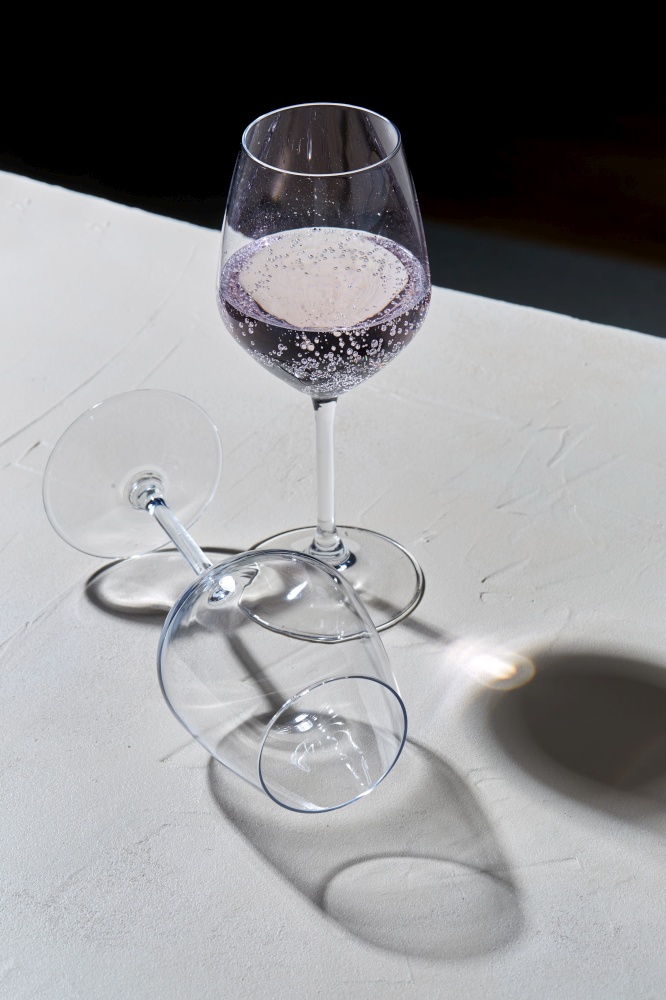 drink, alcohol and glassware concept - wine glasses dropping shadows on white surface. wine glasses dropping shadows on white surface