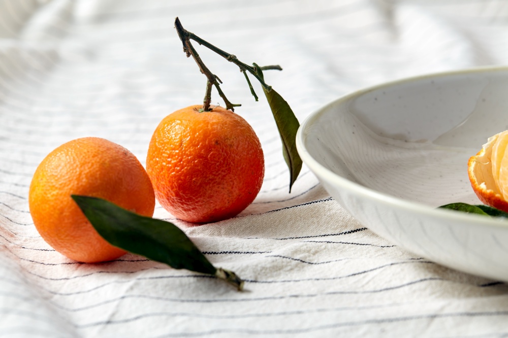food, healthy eating and fruits concept - close up of mandarins on plate over drapery. still life with mandarins on plate over drapery