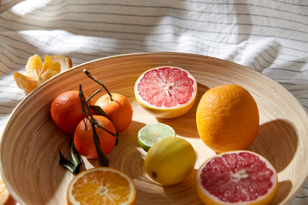 food, healthy eating and vegetarian concept - close up of citrus fruits on wooden plate. close up of citrus fruits on wooden plate