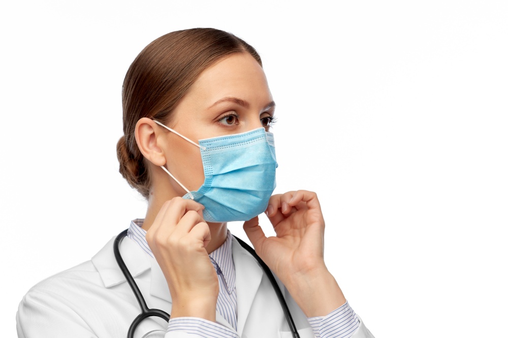 medicine, profession and healthcare concept - female doctor in white coat with stethoscope wearing medical mask. happy female doctor wearing medical mask