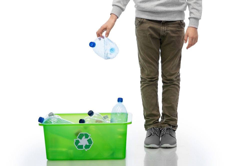recycling, waste sorting and sustainability concept - boy throwing plastic bottle into box over white background. boy throwing plastic bottle into box