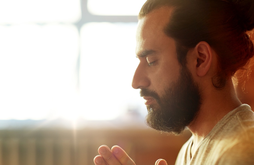 religion, faith and people concept - close up of man meditating at yoga studio. close up of man meditating at yoga studio