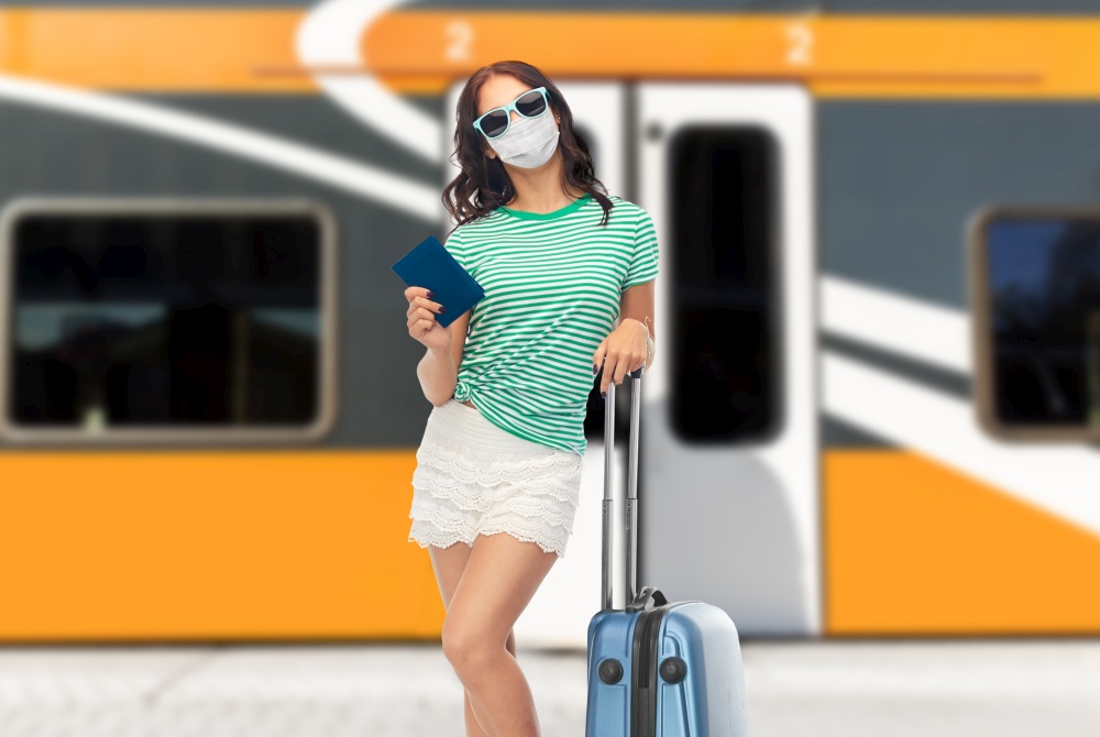 tourism, vacation and health care concept - teenage girl or young woman in protective mask and sunglasses with travel bag and passport over train on railway station on background. teenage girl in mask with travel bag and passport